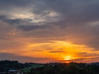 Orange leuchtende Wolkenschichten mit untergehender Sonne
